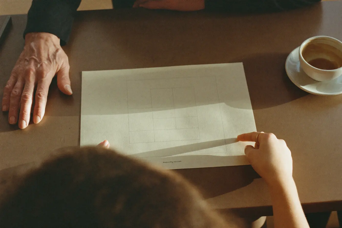 Two people reviewing a printed plan over coffee